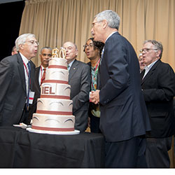IEL board members and president blow out candles on IEL's 50th birthday cake.