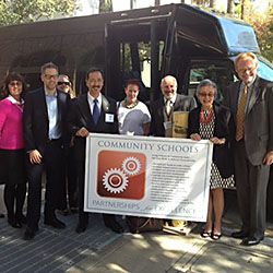 A group of community schools advocates gather in front of a bus with CA State Senator Carol Liu on the Pathways to Partnership Bus Tour.