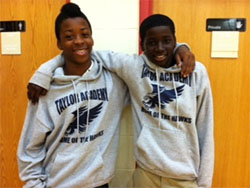 Two high school students at a New York City community school with their arms around each other's shoulders.