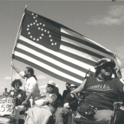 activists waving an American flag with the stars in the shape of a wheelchair logo