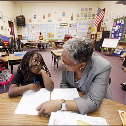 young girl sitting next to her teacher