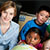 Thumbnail: A teacher sits in a classroom with elementary school students.